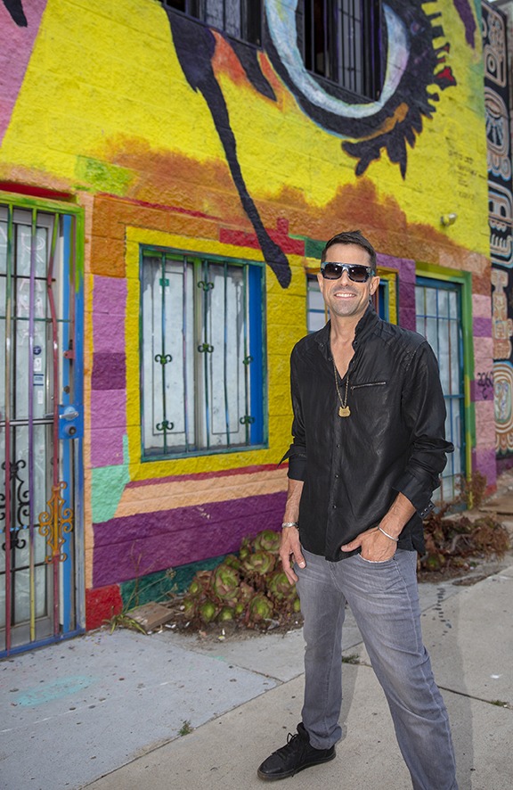 Steve Mulcahy standing in front of a mural, wearing a black jacket and sun glasses